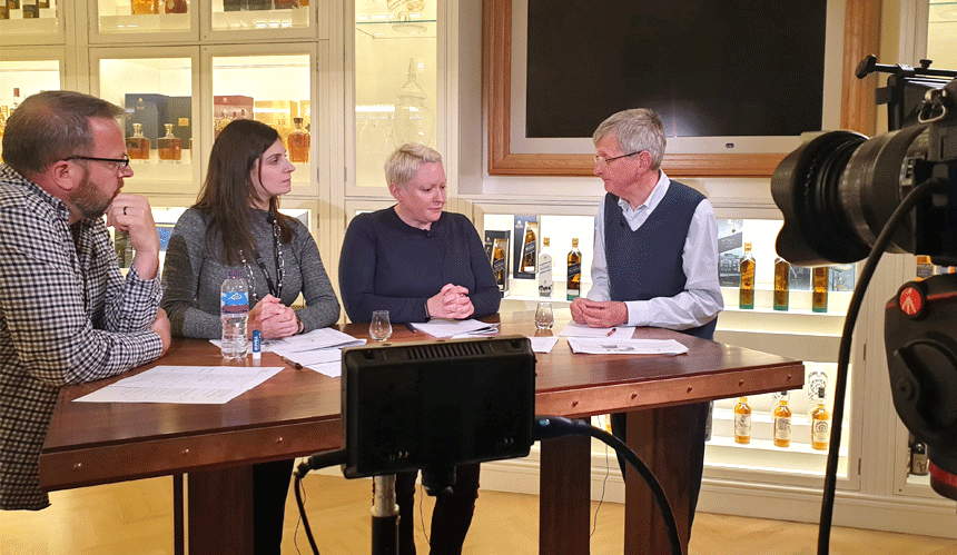 Four people drinking whiskey at a table